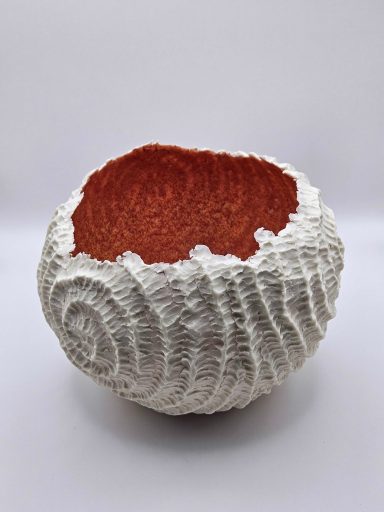 Textured white porcelain bowl with a spiral pattern on the exterior and a smooth, red interior.