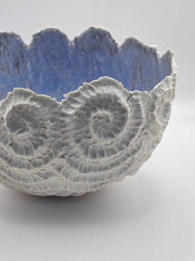 Blue and white porcelain bowl with spiral patter outside and blue interior glaze.